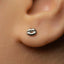 A close-up of a person's ear with a small silver earring featuring a small lip design.
