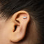 A close-up of a person's ear with a silver earring in the earlobe.