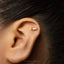 A close-up of a person's ear with a small gold earring in the earlobe.