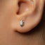 A close-up of a person's ear with a small, silver earring in the earlobe.