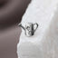 A silver-colored metal watering can charm is placed on a white surface.