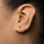 A close-up of a person's ear with a small gold earring featuring the number 4.