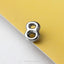 A close-up image of a shiny metal object resembling the number 8, placed on a yellow surface.