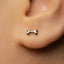 A close-up of a person's ear with a small silver earring in the earlobe.