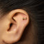 A close-up of a person's ear with a small gold-colored earring in the earlobe.