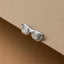 A pair of silver-colored glasses with spiral designs on the temples, placed on a beige surface.