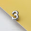 A shiny silver number 3 is placed on a yellow background.