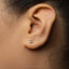 A close-up of a person's ear with a small number 3 earring in it.