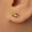 A close-up of a person's ear with a small gold earring in the earlobe.