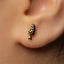 A close-up of a person's ear with a small, gold-colored earring featuring a leaf-like design.