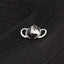 A silver metal mask with a pointed top and curved bottom is displayed on a black fabric surface.