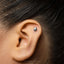 A close-up of a person's ear with a small silver earring in the earlobe.