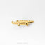 A small gold-colored metal figurine of a crocodile is shown against a white background.