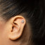 A silver earring with a small symbol on it is visible in the image.