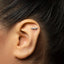 A close-up of a person's ear with a small, silver earring in the earlobe.