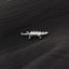 A small silver crocodile-shaped pin is resting on a black fabric surface.