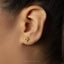 A close-up of a person's ear with a small gold earring featuring a scale of justice symbol.