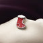 A red enamel Christmas stocking pin is displayed on a white fabric surface against a dark background.