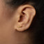 A close-up of a person's ear with a small gold earring featuring a crocodile design.