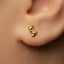 A close-up of a person's ear with a small gold earring featuring a small foot design.