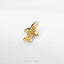 A small gold-colored airplane charm is resting on a white surface.