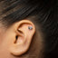 A close-up of a person's ear with a small, heart-shaped earring in the earlobe.