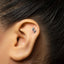 A close-up of an ear with a small silver earring in the earlobe.