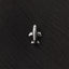A small silver airplane pin is resting on a black fabric surface.