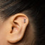 A close-up of an ear with a small silver earring in the earlobe.