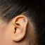 A close-up of a person's ear with a small silver earring in the earlobe.