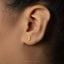 A close-up of a person's ear with a small gold earring in the earlobe.