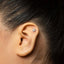 A close-up of a person's ear with a small silver earring in the earlobe.