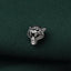 A close-up image of a silver tiger head pin or brooch against a dark green fabric background.