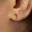A close-up of a person's ear with a small gold earring in the earlobe.