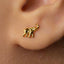 A close-up of a person's ear with a small gold elephant earring in the earlobe.