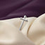A silver cross-shaped object is resting on a beige fabric surface.