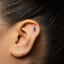 A close-up of an ear with a small, silver earring in the earlobe.