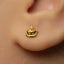 A close-up of a person's ear wearing a small gold earring shaped like a coffee cup.