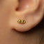 A close-up of a person's ear with a small gold earring in the earlobe.