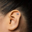 A close-up of a person's ear with a small silver earring in the earlobe.