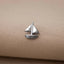 A small silver metal boat pin is resting on a beige fabric surface.