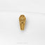 A gold-colored embossed keychain or pin with an intricate design, placed on a white surface.