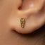 A close-up of a person's ear with a small gold earring featuring an embossed design.