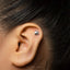 A close-up of a person's ear with a small silver earring in the earlobe.