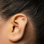A close-up of a person's ear with a small silver earring in the earlobe.