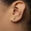 A close-up view of a person's ear with a small gold earring in the earlobe.
