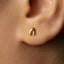 A close-up of a person's ear with a small gold earring in the earlobe.