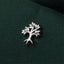 A close-up image of a small silver tree-like emblem or pin resting on a dark green fabric.