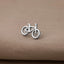 A silver bicycle symbol is displayed on a beige fabric surface.