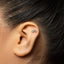 A silver earring with a bicycle design is visible in the person's ear.